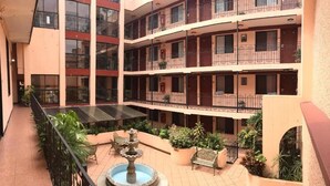 A multi-level courtyard with a central fountain, outdoor seating, and balconies. - Hotel San Angel Puebla (Puebla)