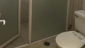 A bathroom with a glass-enclosed shower, a toilet with a sign, and a towel hanging on the shower door. - Hotel San Angel Puebla (Puebla)