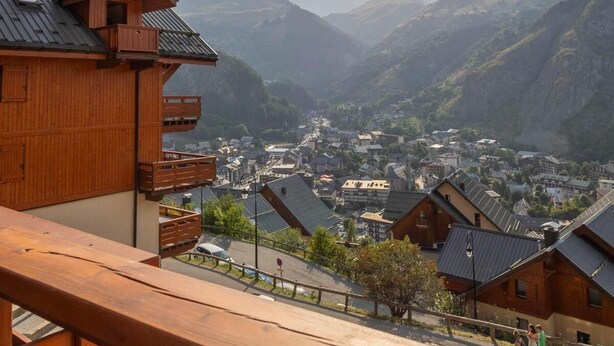 Ein Holzhaus mit Balkon und Blick auf ein Tal und Berge.