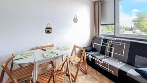 Un ambiente compatto con angolo pranzo, divano dai motivi geometrici e una grande finestra vista esterna.