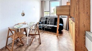 Un ambiente compatto con un tavolo da pranzo, due sedie, un divano e un letto a castello.