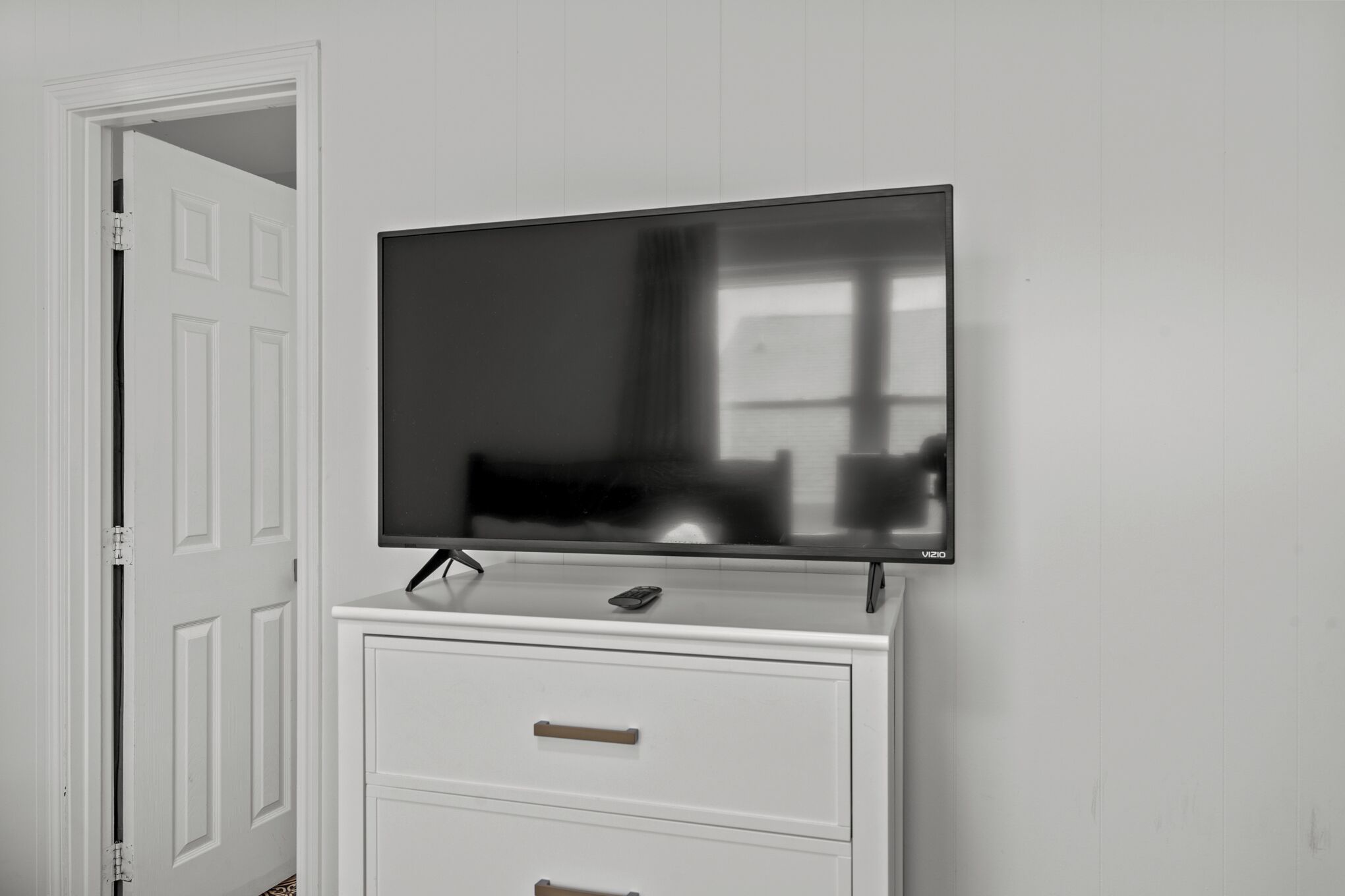 Televisor de pantalla plana montado en un mueble blanco con dos cajones.