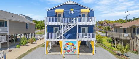 En toetages bygning med en balkon og et muralmaleri af en strandscene.