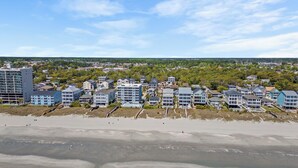 Une zone hôtelière située sur la côte, avec des établissements donnant sur la plage, une plage de sable et une vue sur l’océan.