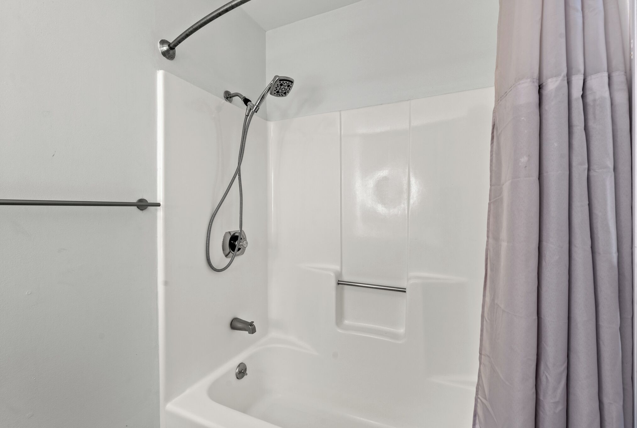 Un espace douche moderne doté d’un pommeau de douche à main, d’un siège intégré et d’un panneau de commande.