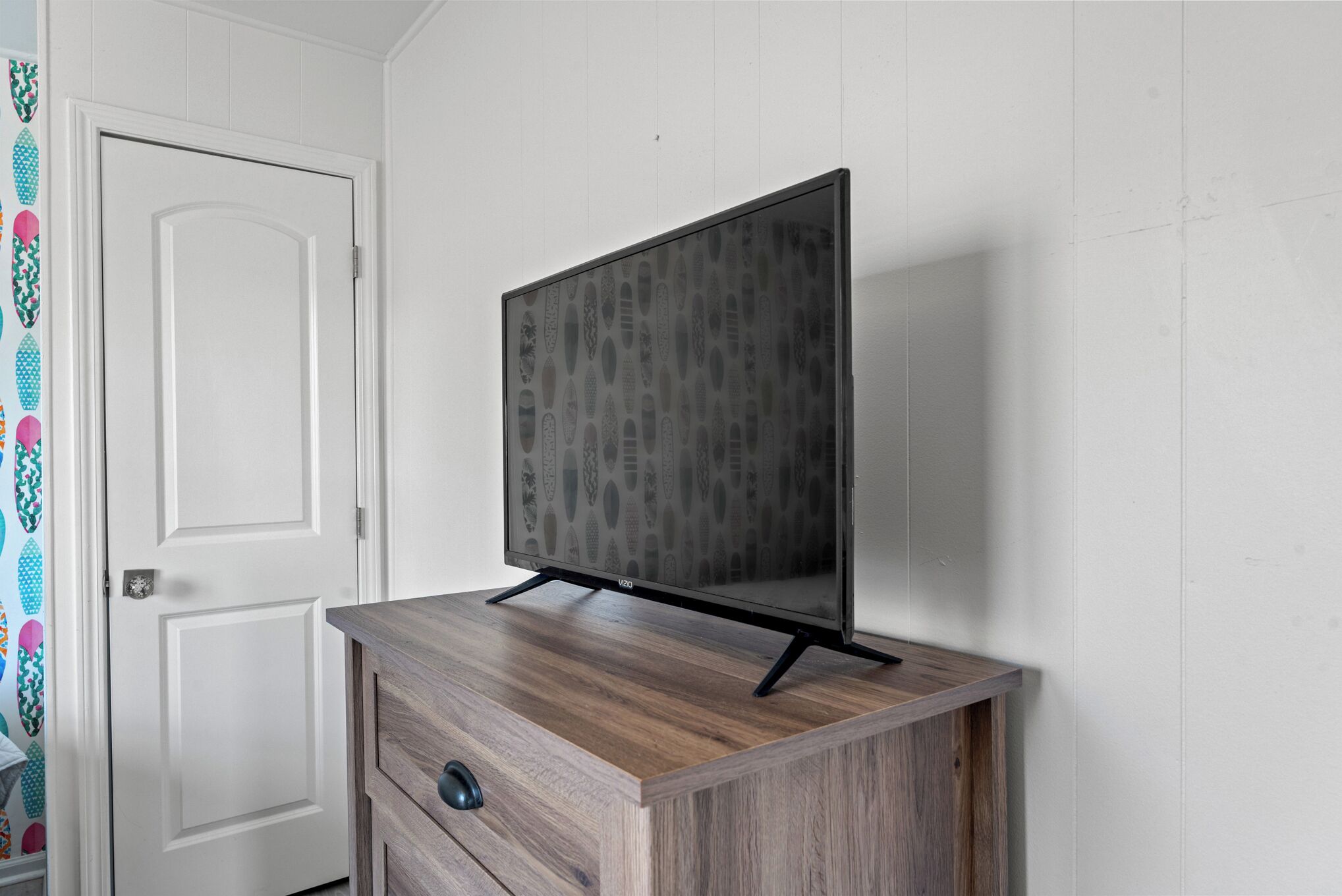 Ein Fernseher steht auf einer Holzkommode vor einer weißen Wand.