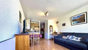 A compact living space with a kitchenette, a dining area, and a sofa.
