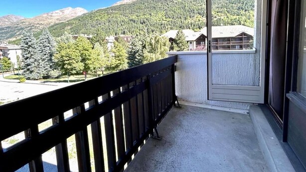 A balcony with a view of a mountain and forest.