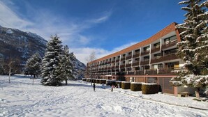 A hotel with a modern design, featuring multiple balconies and a snow-covered landscape.