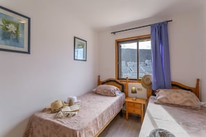 Un dormitorio con dos camas, una ventana con vistas y una mesita de noche con lámpara.