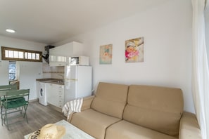 Un espacio habitable compacto con kitchenette, sofá, comedor y lavadora.