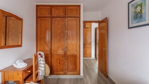 A room with a wooden wardrobe, a desk with a telephone, and a bed. - Cumana 2 Apartment with Terrace (Puerto Rico)