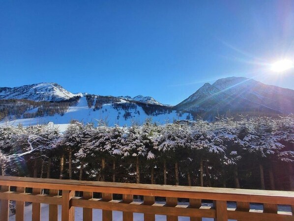 A mountain landscape with a clear sky and a sun shining from the right.