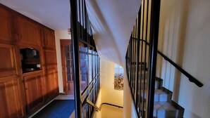 A staircase with a black railing, wooden walls, and a bench at the bottom.