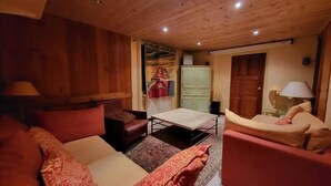 A cozy room with wooden walls and ceiling, a sofa, a chair, a small table, and a cabinet.