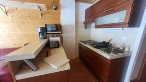 A compact kitchen with wooden cabinets, a microwave, a coffee maker, and a sink. - 300m from ski slopes, Ground floor, view parking, terrace, parking, tv, ski locker, 29m² (Montgenèvre)