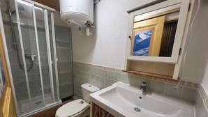 A bathroom with a shower, toilet, sink, and a mirror above the sink. - 300m from ski slopes, Ground floor, view parking, terrace, parking, tv, ski locker, 29m² (Montgenèvre)