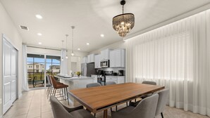 Una cocina moderna con armarios blancos, una mesa de comedor de madera y sillas grises.