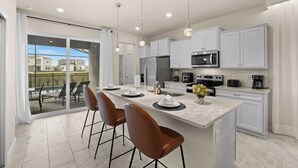 Una cocina moderna con armarios blancos, una isla grande y un comedor con sillas.