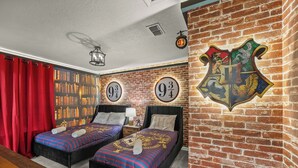 Una habitación con dos camas, una estantería y un escudo de Gryffindor en la pared.