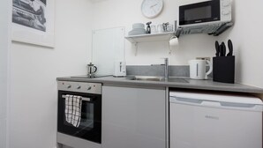Een kleine keuken met een magnetron, oven en vaatwasser.