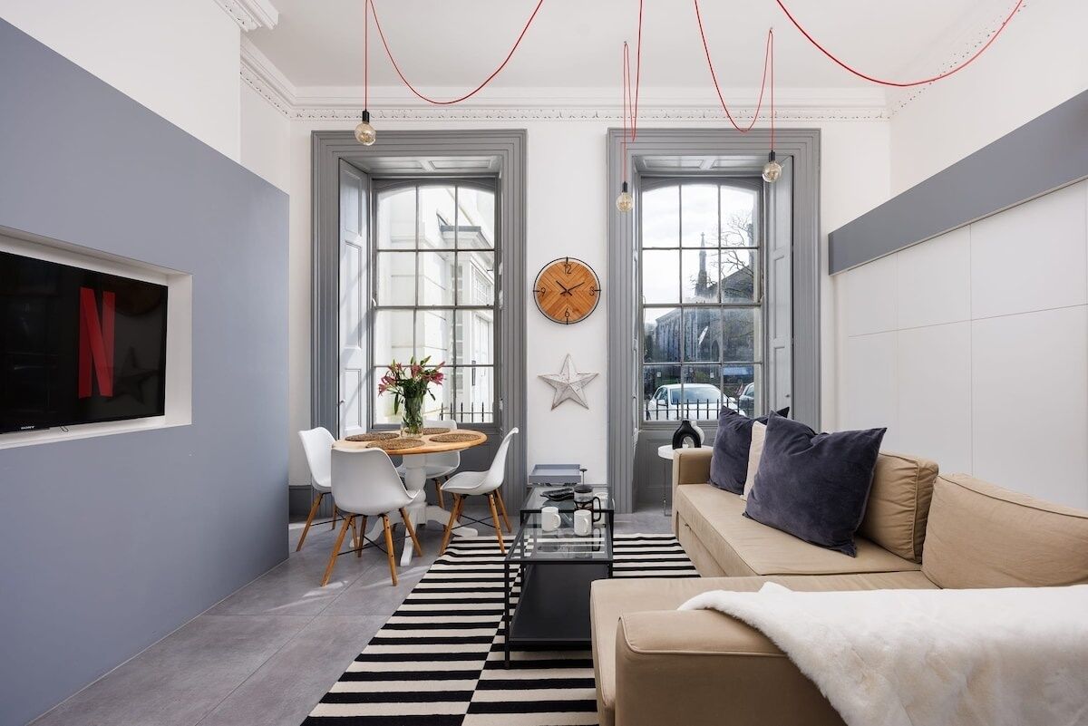 Een moderne woonkamer met een bank, een salontafel en een eethoek met stoelen en een tafel.