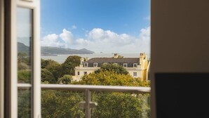 Blick auf die Küste vom Fenster aus, mit Blick auf ein Gebäude, einen Balkon, Bäume und einem klaren Himmel.
