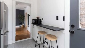 A modern kitchen with a black countertop, two wooden stools, and a refrigerator. - Hotel Quality/ Walkable / Free Parking/ Office #7 (Lakewood)
