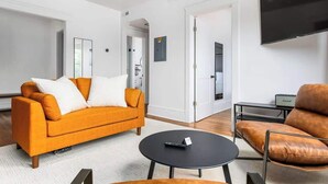 A modern living room with a sofa, a coffee table, and a TV. - Hotel Quality/ Walkable / Free Parking/ Office #7 (Lakewood)