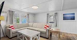 A modern living room with a sectional sofa, a small table, and a view of the outside. - Cabana Beach - RR Beach Club LLC (North Myrtle Beach)