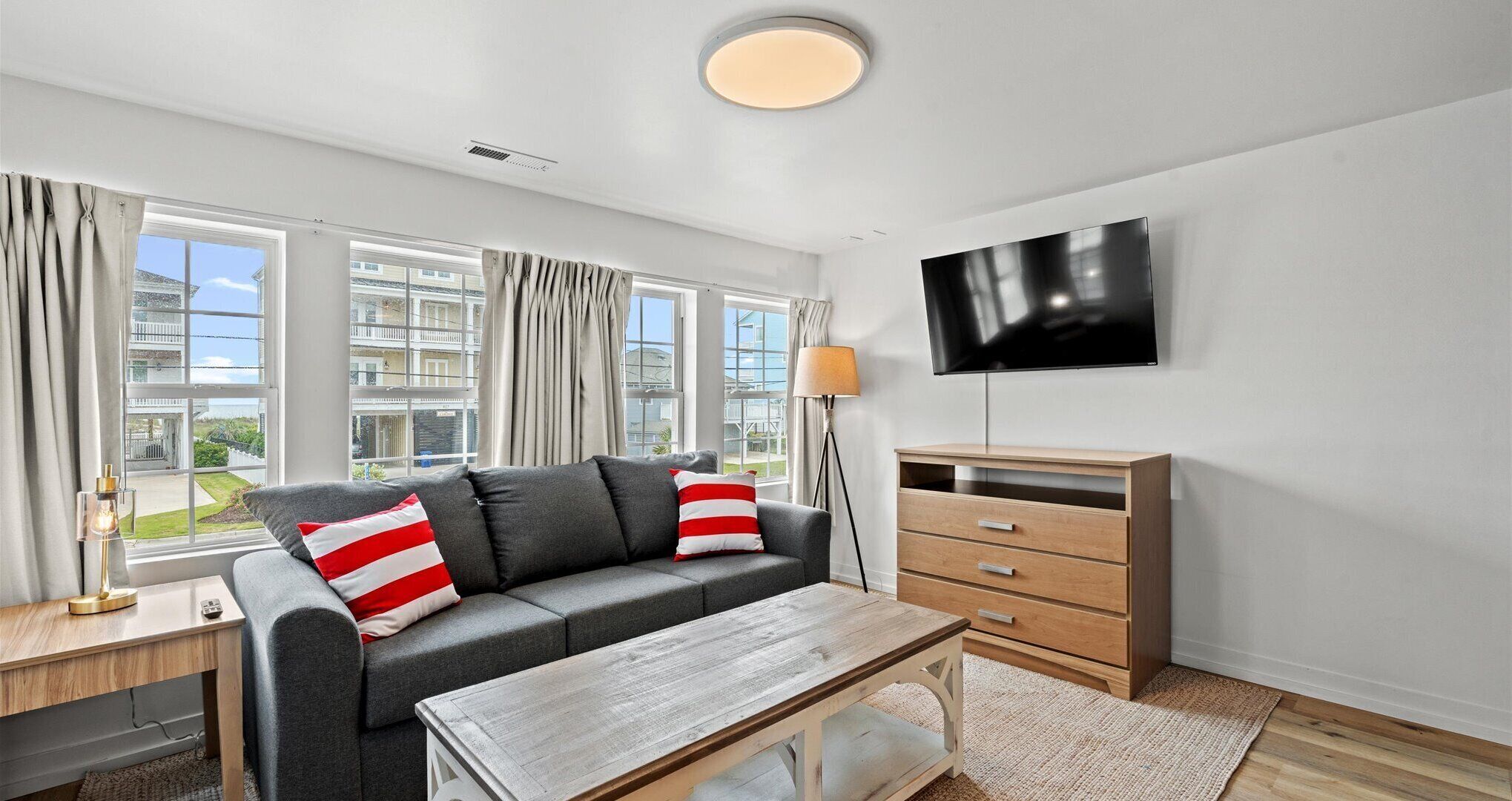 A modern living room with a grey sofa, wooden coffee table, and a TV mounted on the wall.