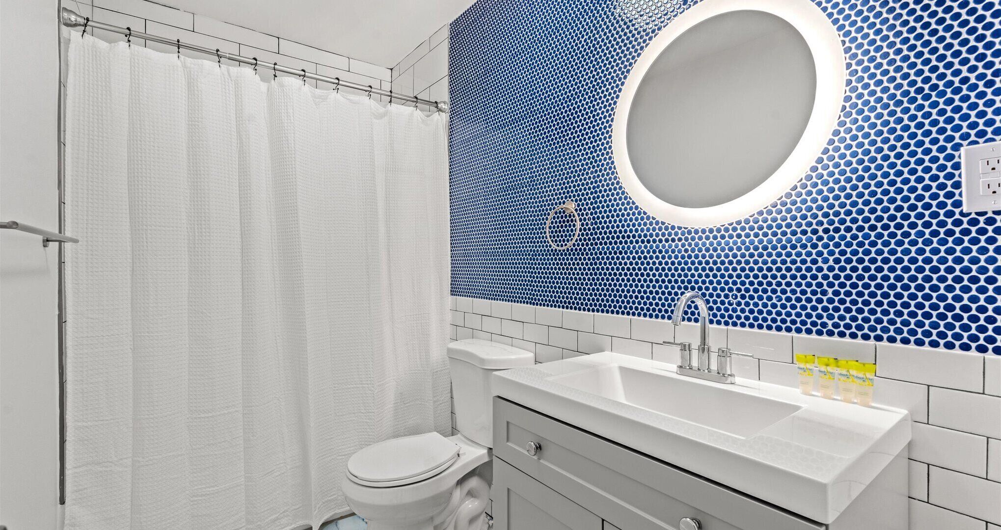 Un bagno con il water bianco, un lavandino con specchio e una tenda da doccia.