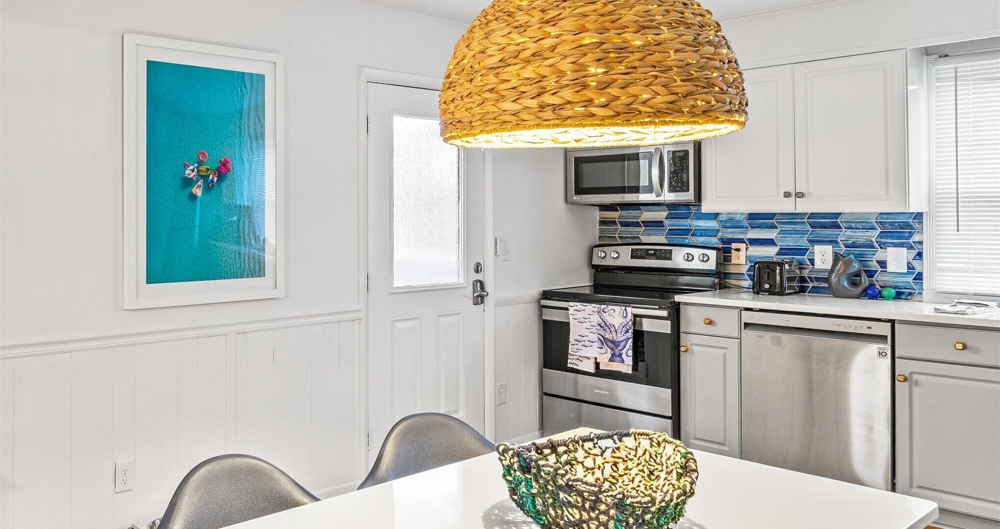 A modern kitchen with white cabinetry, a stainless steel oven, a microwave, and a toaster.