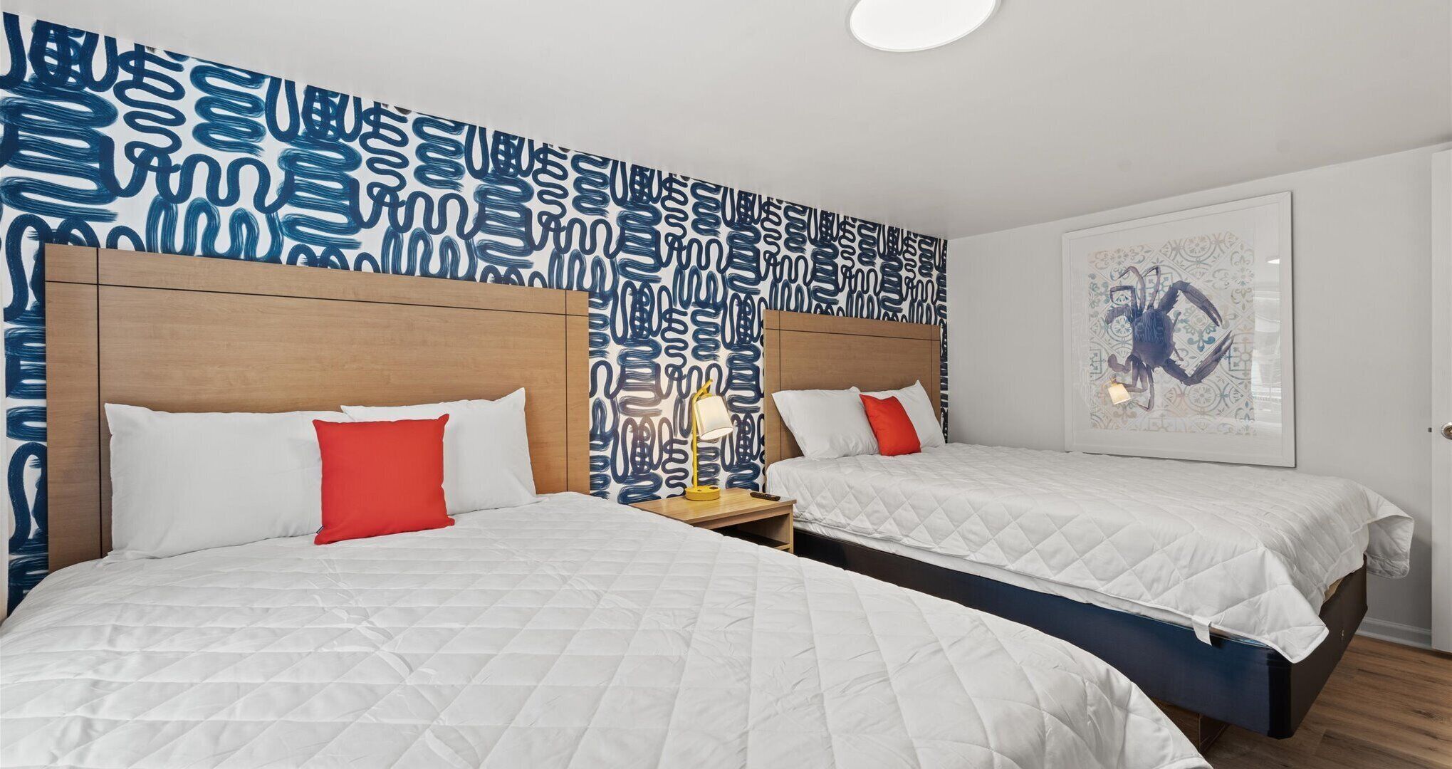 Ein Hotelzimmer mit zwei Betten, einer Wand mit Muster und einem gerahmten Kunstwerk.
