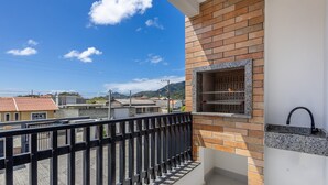 Ein Balkon mit einer Backsteinmauer, einem Grill und Blick auf die Umgebung.