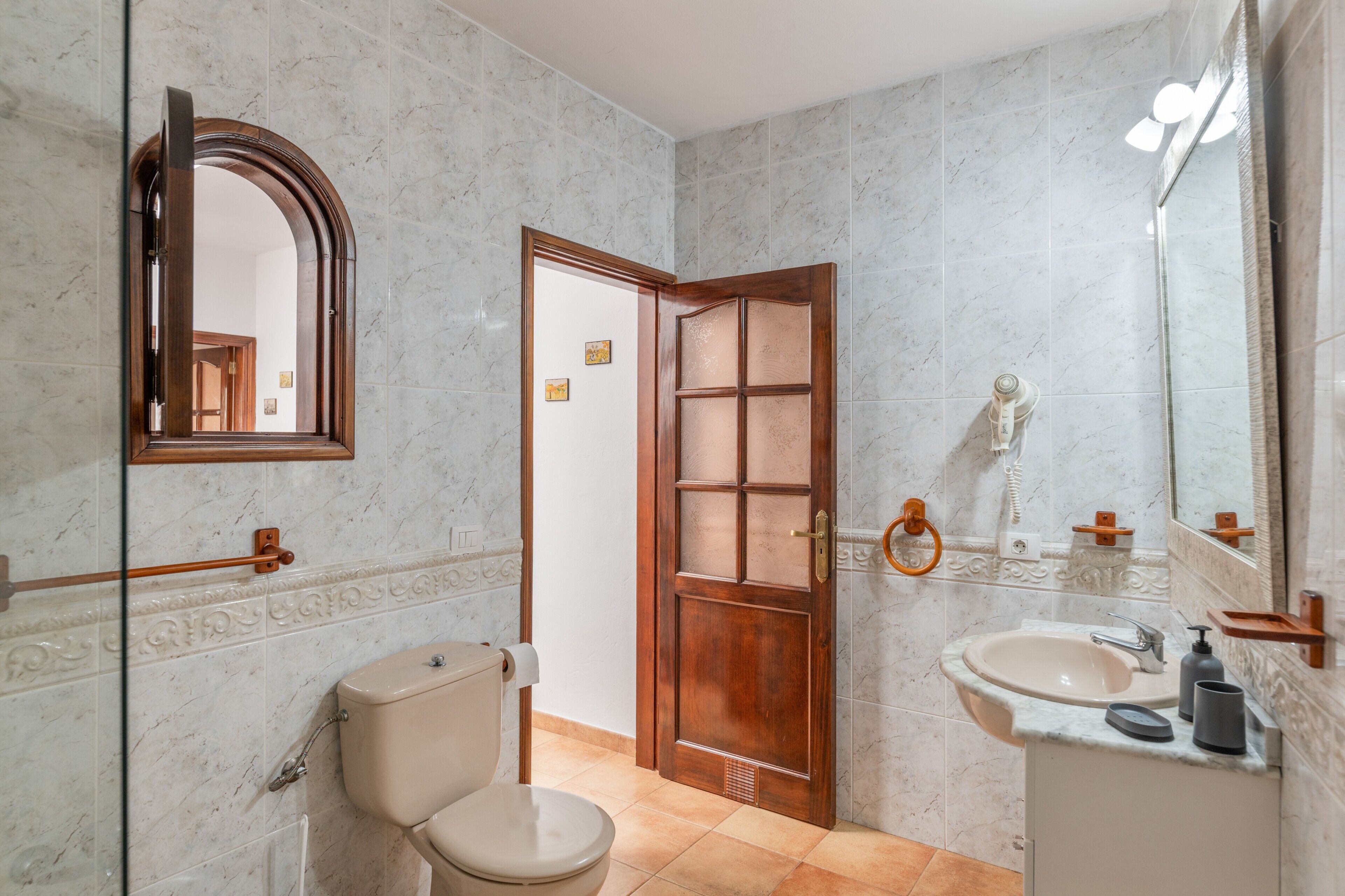 Een badkamer met toilet, wastafel, spiegel en een houten deur.