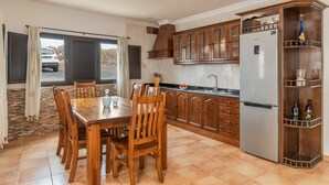 Una cocina con gabinetes de madera, un refrigerador de acero inoxidable y una mesa de comedor con sillas.