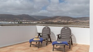 Una terraza con dos sillas y una mesa, con vistas a un paisaje montañoso.