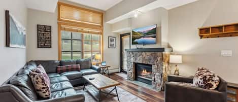 A modern living room with a sectional sofa, a fireplace, and a large window.