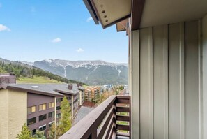 Ein Balkon mit Blick auf eine gebirgige Landschaft und Wohnhäuser.