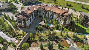 Ein Luftbild eines mehrstöckigen Hotels mit Innenhof, Schwimmbad und umliegender Bepflanzung.