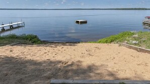 A sandy beach with a dock and a small boat in the water.