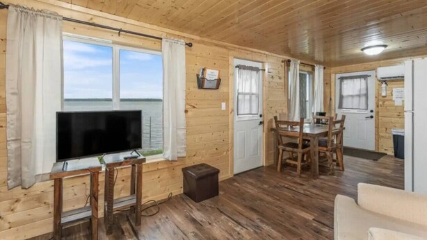 A wooden cabin with a TV, dining table, and chairs.