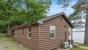A small, single-story cabin with a brown exterior, a visible number '5738' sign, and a small porch area.