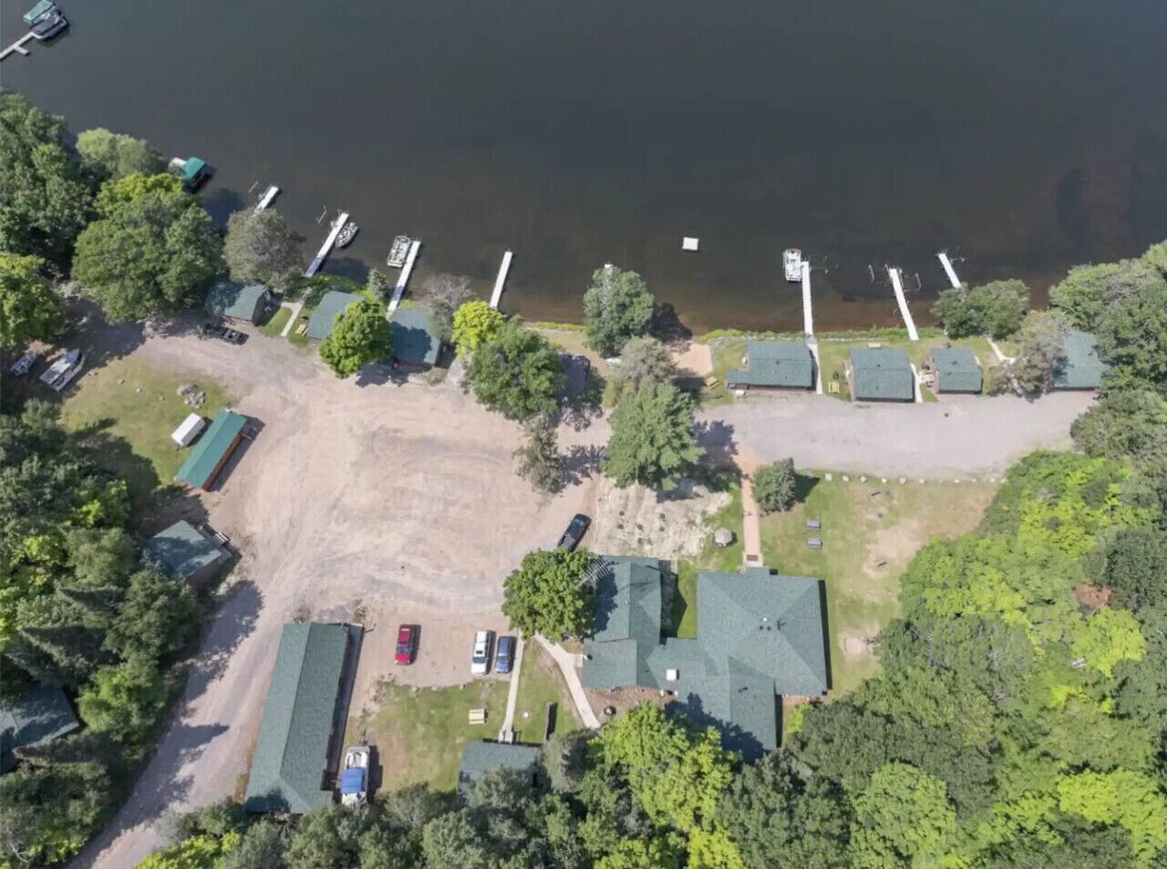 Vue aérienne d’un terrain de camping comprenant plusieurs cabanes, un espace de stationnement et un quai.