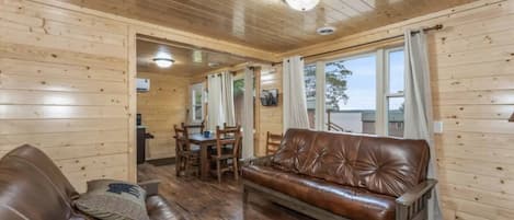 A wooden interior with a leather sofa, dining table, and chairs.