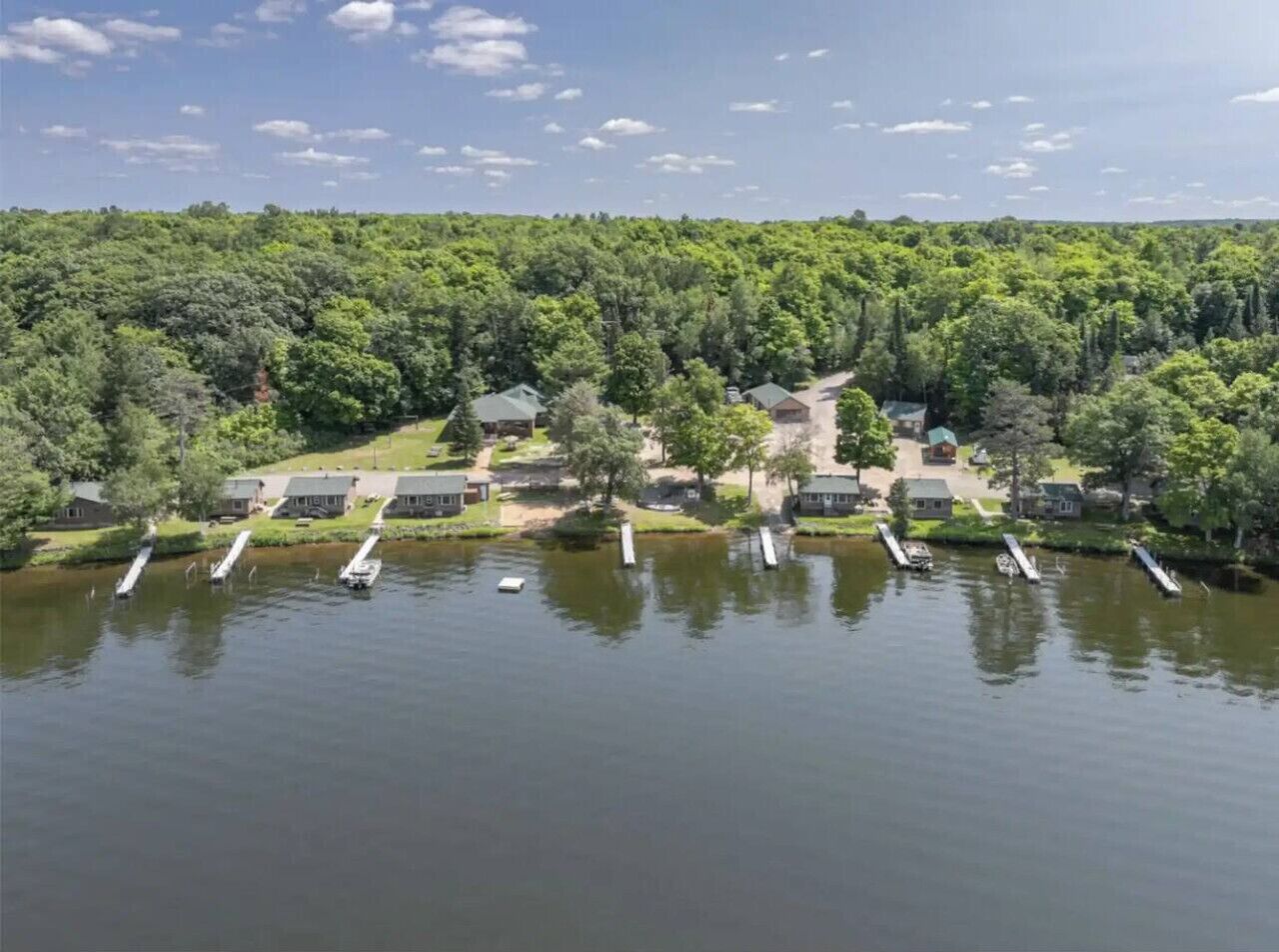 A lakeside resort with multiple cabins and a dock with boats.