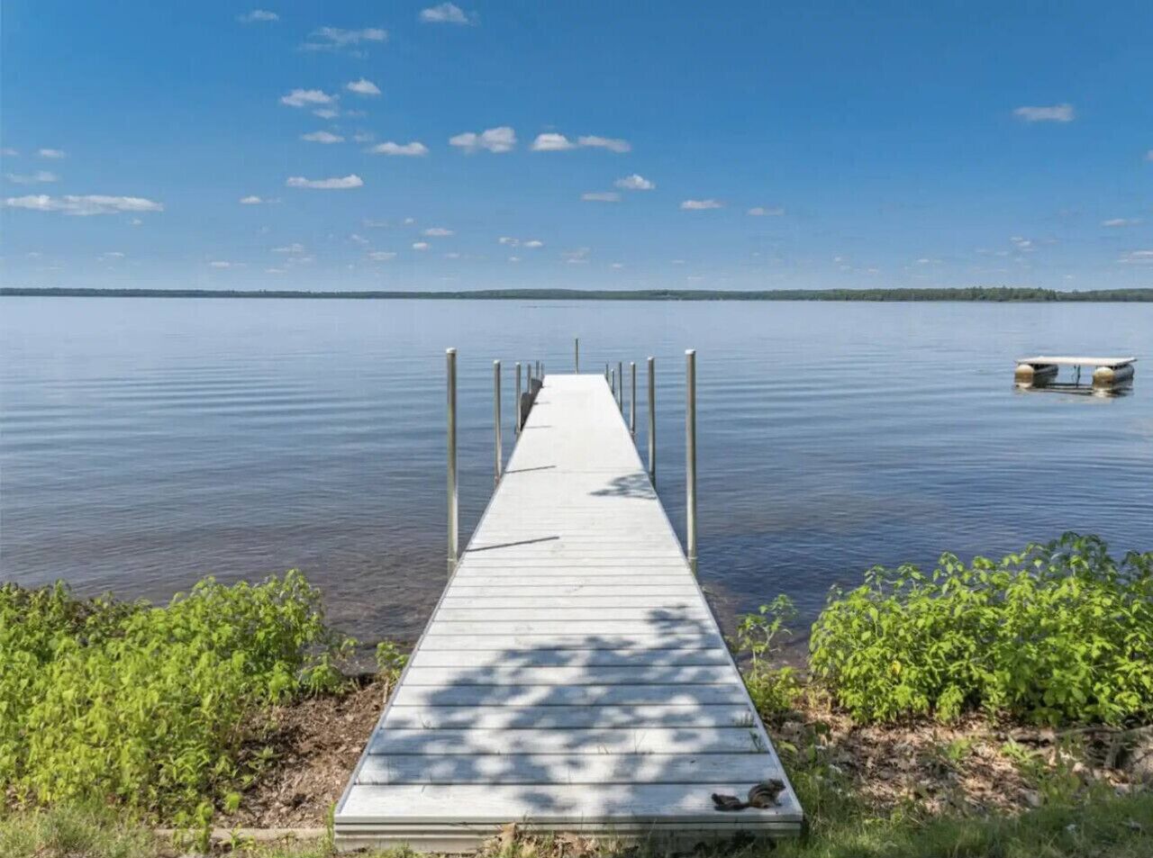 A wooden pier extending into calm water with a boat docked at the end.