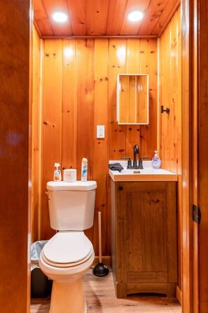 Un bagno con rivestimento in legno, dotato di WC, lavandino e mobile.