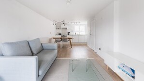 Un appartement moderne avec un canapé gris, un coin repas et une cuisine.